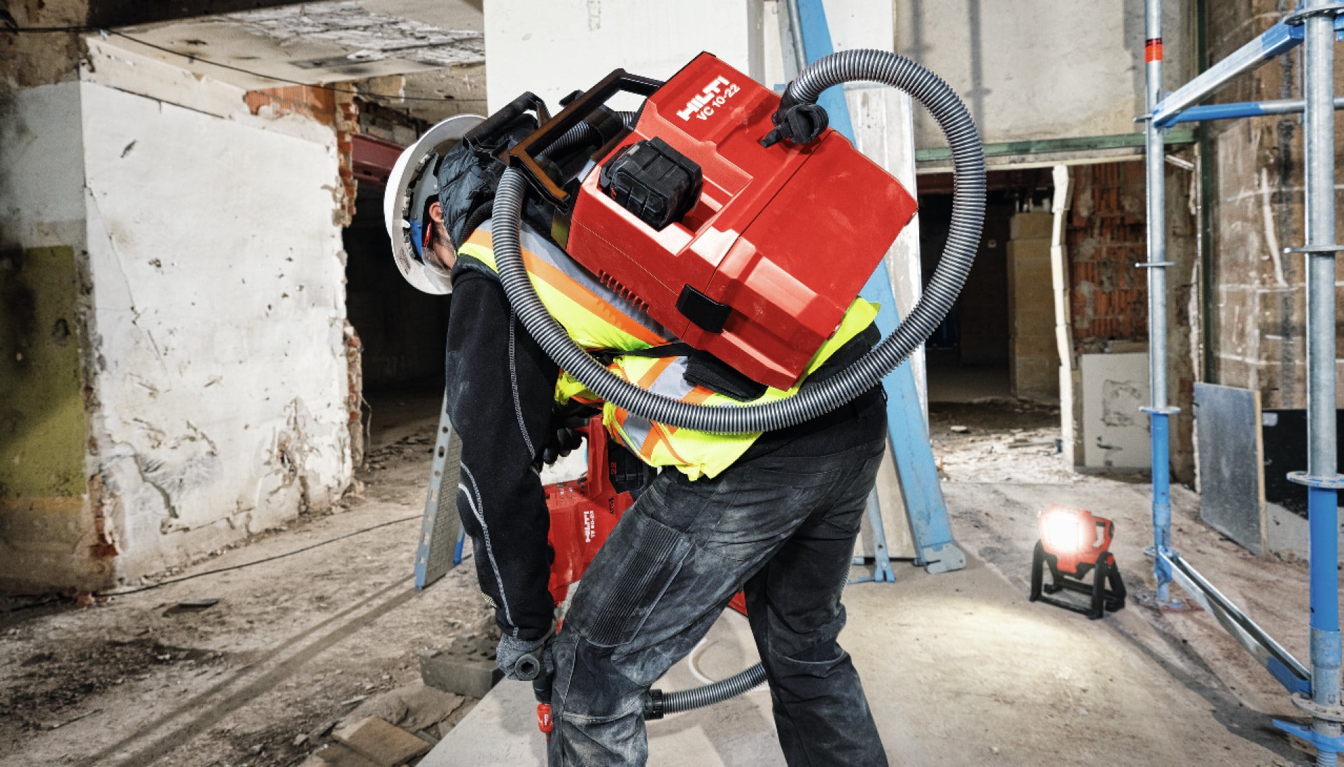 a worker uses a cordless vacuum cleaner to remove dust from demolition work