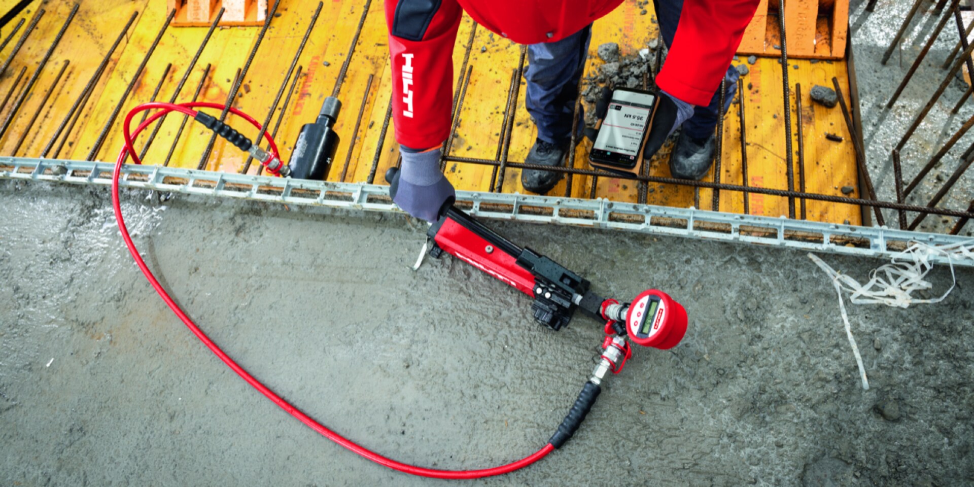On-site anchor testing equipment with wireless data transfer to a smartphone being used in a concrete floor slab